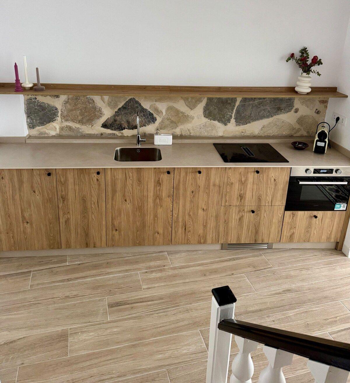 Cocina con frente de piedra y muebles de madera
