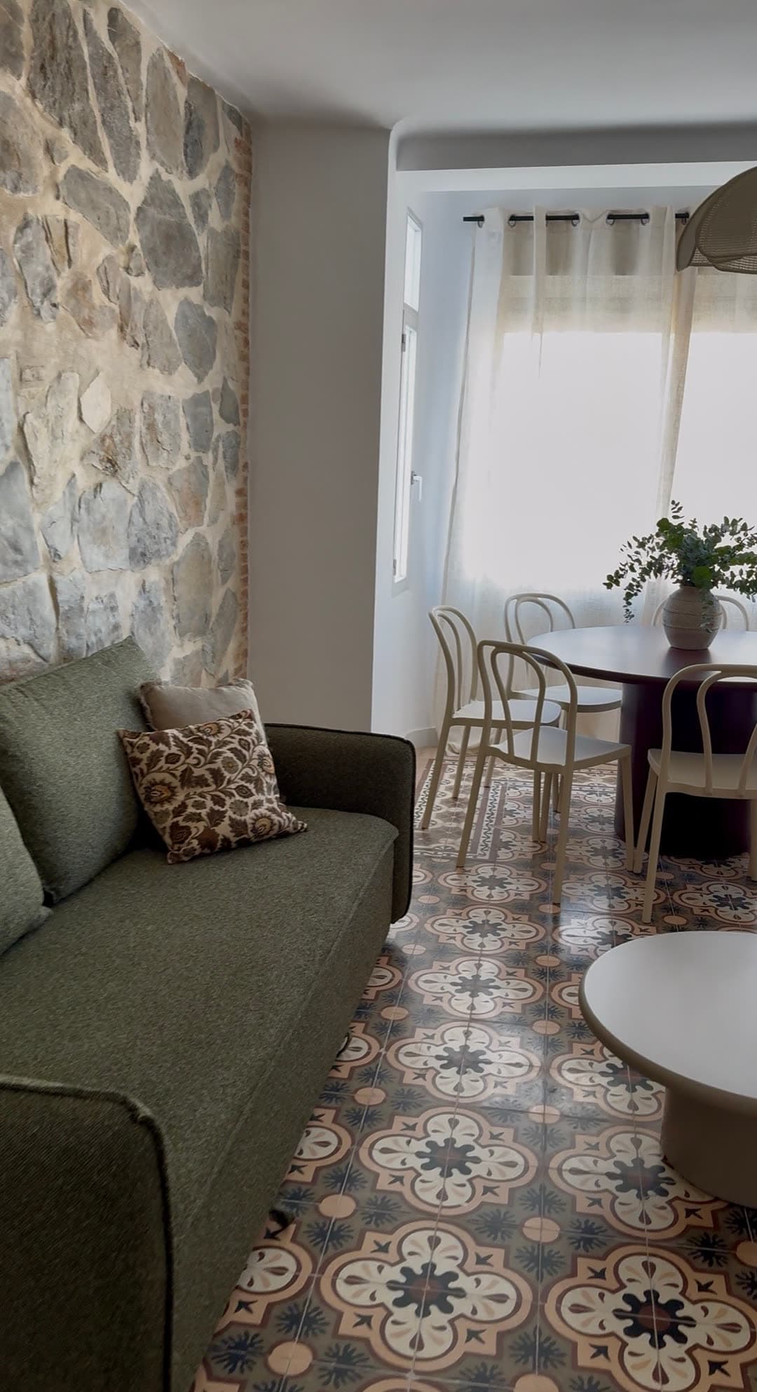 Salón con sofá verde y pared de piedra